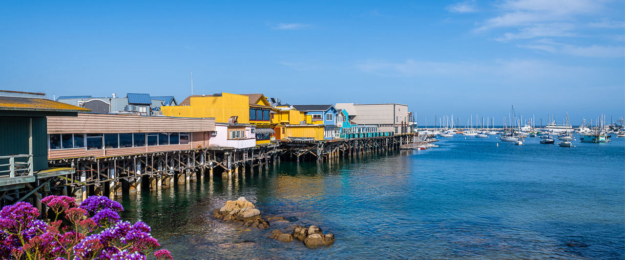 View of colorful waterfront buildings along a pier over calm coastal water.
