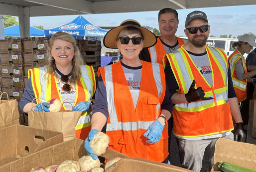 Volunteers wearing safety vests sorting fresh produce at a community food distribution event