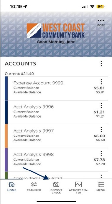 West Coast Community Bank mobile app's home page after login with a list of accounts with current and available balances. A footer consists of: Home, Transfer, Deposit Check, Activity Center and Menu. Deposit Check is noted.